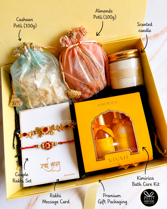 A curated gift box set labeled with callouts for each included item: a light blue drawstring pouch of cashews, a peach drawstring pouch of almonds, a scented candle, a Rakhi set on a white card, a message card, and a kimurica bath care kit in a yellow box. The set is arranged inside a yellow gift box with decorative ribbon and tissue paper.